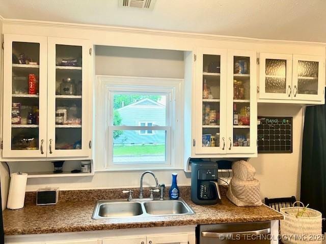 2201 Baugh St, Muskogee, OK 74403 - kitchen with a sink, stainless steel dishwasher, glass insert cabinets, white cabinets, and dark countertops
