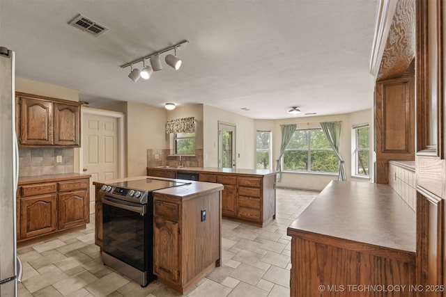 4157 New Prue Rd, Sand Springs, OK 74063 - kitchen with appliances with stainless steel finishes, brown cabinets, a center island, backsplash, and a peninsula