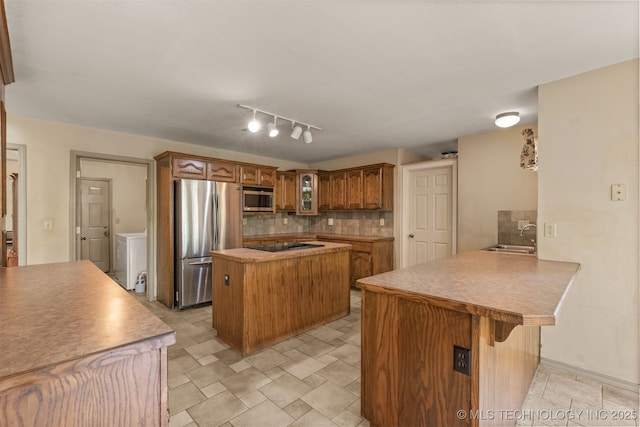 4157 New Prue Rd, Sand Springs, OK 74063 - kitchen with appliances with stainless steel finishes, a peninsula, a sink, a breakfast bar area, and decorative backsplash