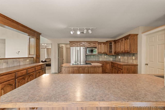 4157 New Prue Rd, Sand Springs, OK 74063 - kitchen featuring appliances with stainless steel finishes, a center island, brown cabinetry, and backsplash