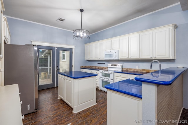 1020 N 3rd, Durant, OK 74701 - kitchen featuring white appliances, dark countertops, dark wood-style flooring, a center island, and white cabinetry