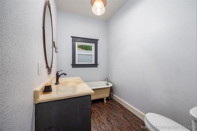 1020 N 3rd, Durant, OK 74701 - bathroom with toilet, vanity, wood finished floors, a freestanding bath, and baseboards
