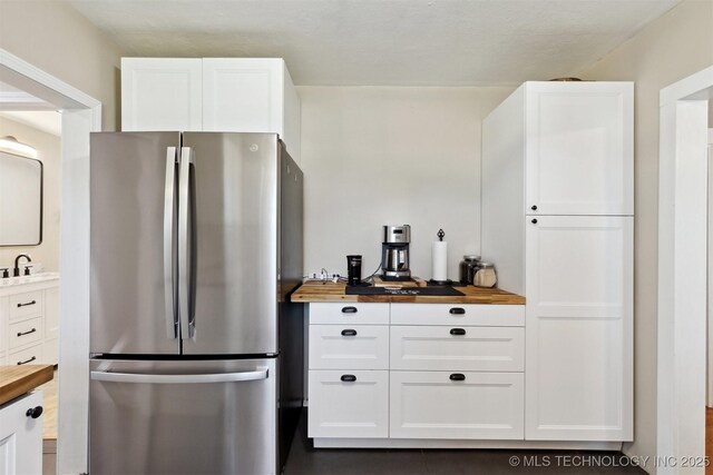 780452 S 3530, Cushing, OK 74023 - kitchen featuring freestanding refrigerator, wood counters, white cabinetry, and a sink