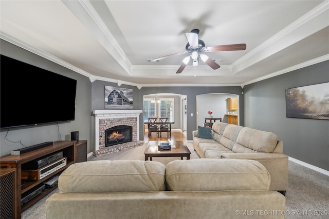 26233 E 114th Pl, Coweta, OK 74429 - living room featuring arched walkways, crown molding, a raised ceiling, ceiling fan, and carpet flooring