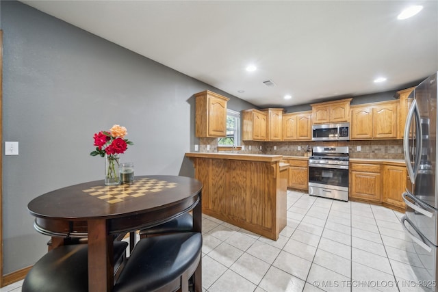26233 E 114th Pl, Coweta, OK 74429 - kitchen with stainless steel appliances, a peninsula, tasteful backsplash, light tile patterned flooring, and recessed lighting