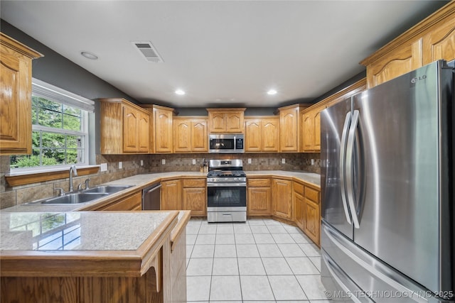 26233 E 114th Pl, Coweta, OK 74429 - kitchen featuring appliances with stainless steel finishes, a sink, light tile patterned floors, tasteful backsplash, and a peninsula