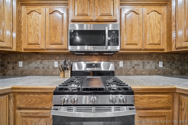 26233 E 114th Pl, Coweta, OK 74429 - kitchen with appliances with stainless steel finishes, decorative backsplash, brown cabinets, and tile counters
