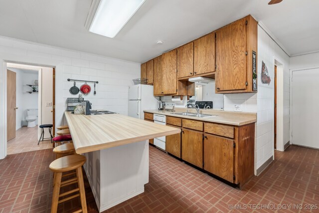 370463 E 5750th Rd, Terlton, OK 74081 - kitchen featuring brick patterned flooring, a sink, brown cabinetry, ornamental molding, and a breakfast bar area