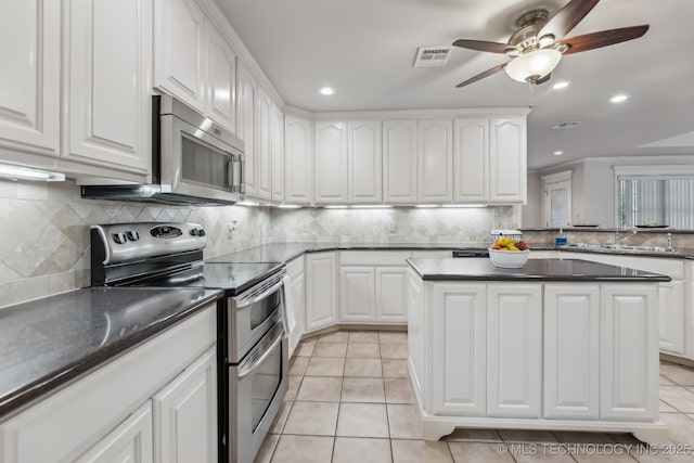 370463 E 5750th Rd, Terlton, OK 74081 - kitchen with stainless steel appliances, a kitchen island, ceiling fan, backsplash, and light tile patterned flooring