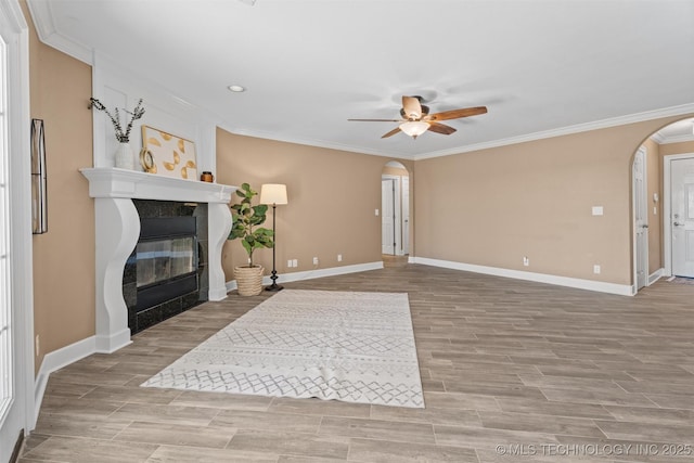 28744 N 3964th Rd, Ochelata, OK 74051 - unfurnished living room featuring arched walkways, a ceiling fan, ornamental molding, a tiled fireplace, and baseboards