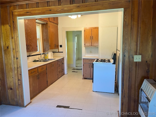 701 NW 3rd St, Stigler, OK 74462 - kitchen featuring white range with gas stovetop, a sink, heating unit, light countertops, and brown cabinetry