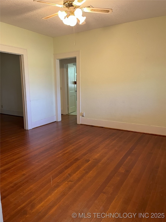 701 NW 3rd St, Stigler, OK 74462 - empty room featuring baseboards, dark wood finished floors, a ceiling fan, and a textured ceiling