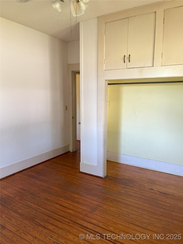 701 NW 3rd St, Stigler, OK 74462 - unfurnished bedroom with baseboards, wood finished floors, and attic access