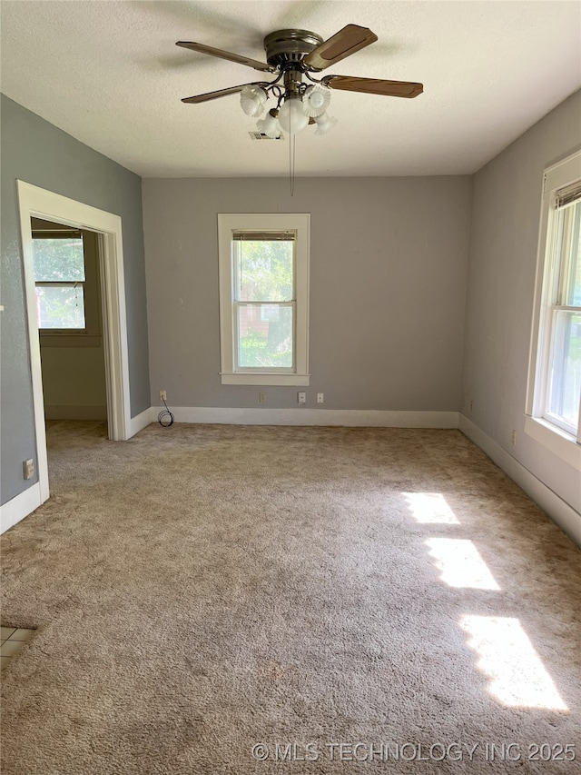 701 NW 3rd St, Stigler, OK 74462 - empty room with healthy amount of natural light, ceiling fan, carpet floors, baseboards, and a textured ceiling