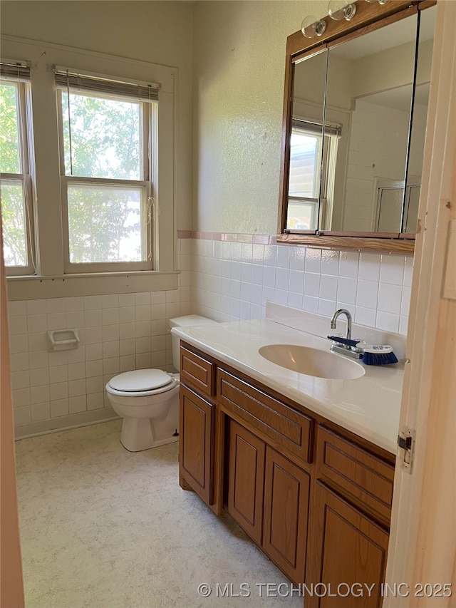 701 NW 3rd St, Stigler, OK 74462 - bathroom with tile walls, plenty of natural light, vanity, and toilet