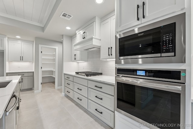 23250 E 106th Pl S, Broken Arrow, OK 74014 - kitchen with appliances with stainless steel finishes, recessed lighting, custom exhaust hood, decorative backsplash, and light tile patterned flooring