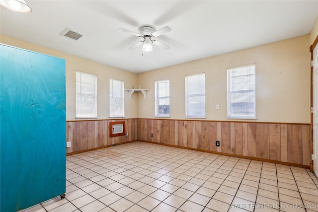 8805 E 46th Pl, Tulsa, OK 74145 - empty room featuring wainscoting, ceiling fan, wooden walls, heating unit, and light tile patterned flooring