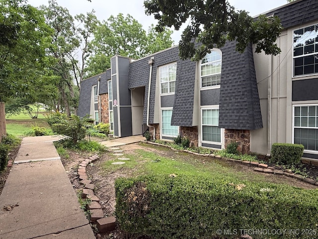 4428 E 68th St Unit 484, Tulsa, OK 74136 - view of front facade featuring stone siding, roof with shingles, and mansard roof