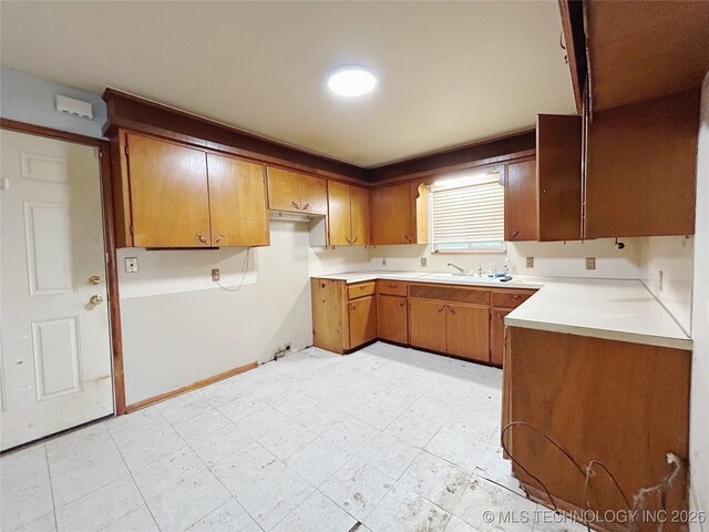 303 W Mckinley Ave, Sapulpa, OK 74066 - kitchen with brown cabinetry, a sink, and light countertops