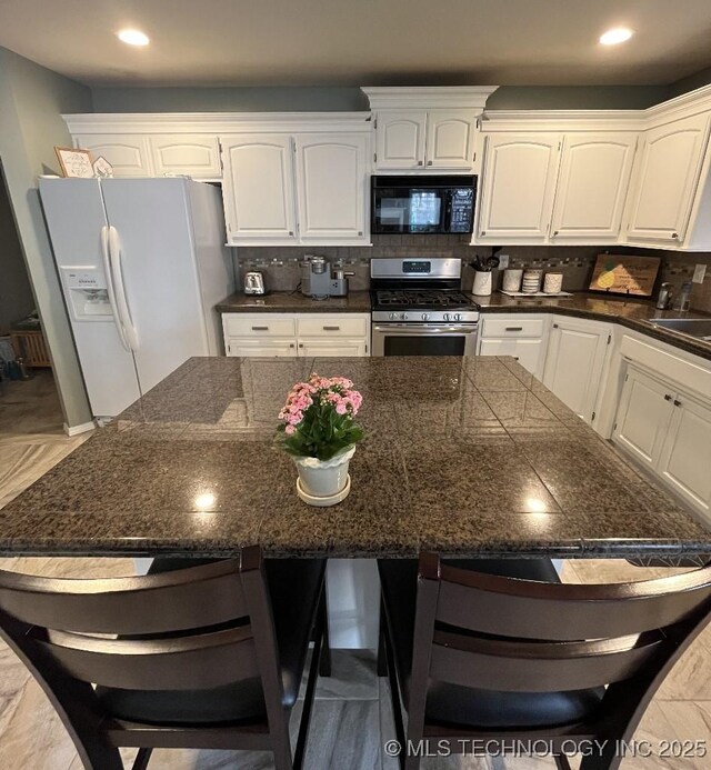 19416 E 38th St S, Broken Arrow, OK 74014 - kitchen with stainless steel gas range oven, white fridge with ice dispenser, black microwave, dark countertops, and a kitchen breakfast bar