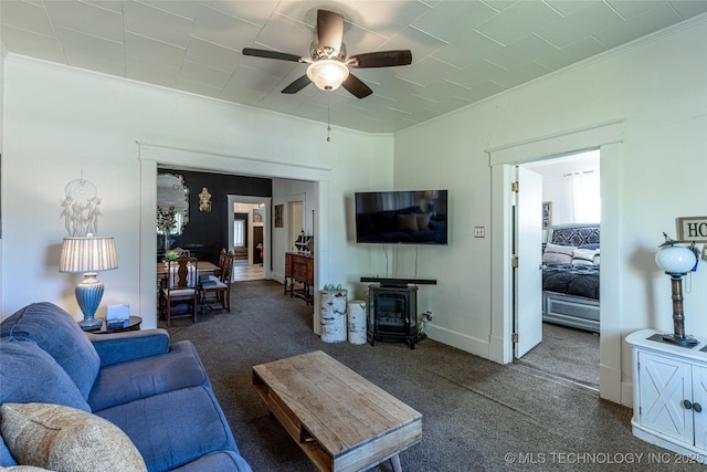 317 E 4th St, Claremore, OK 74017 - carpeted living area featuring crown molding, ceiling fan, a wood stove, and baseboards