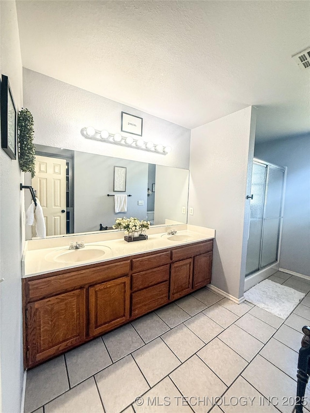 27434 E 113th St, Coweta, OK 74429 - full bath with tile patterned floors, double vanity, a shower stall, baseboards, and a textured ceiling