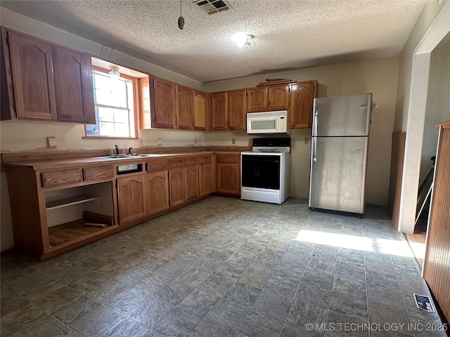 621 S 3rd St, Morris, OK 74445 - kitchen with stove, white microwave, freestanding refrigerator, a sink, and a textured ceiling