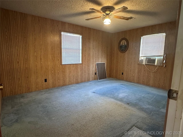 621 S 3rd St, Morris, OK 74445 - carpeted empty room featuring a ceiling fan, plenty of natural light, cooling unit, wooden walls, and a textured ceiling
