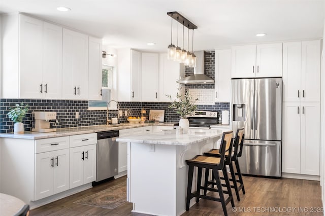 9110 E 37th Ct, Tulsa, OK 74145 - kitchen featuring appliances with stainless steel finishes, wall chimney range hood, dark wood-style flooring, a kitchen bar, and recessed lighting