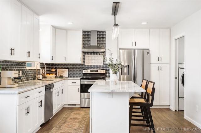 9110 E 37th Ct, Tulsa, OK 74145 - kitchen with wall chimney exhaust hood, appliances with stainless steel finishes, a sink, wood finished floors, and a kitchen bar
