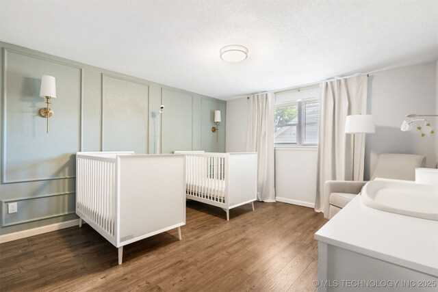 9110 E 37th Ct, Tulsa, OK 74145 - bedroom featuring wood finished floors, a sink, baseboards, and a decorative wall