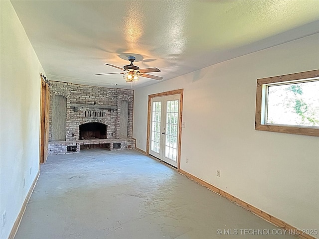 1107 SE 5th St, Wagoner, OK 74467 - unfurnished living room with french doors, baseboards, a fireplace, ceiling fan, and concrete floors