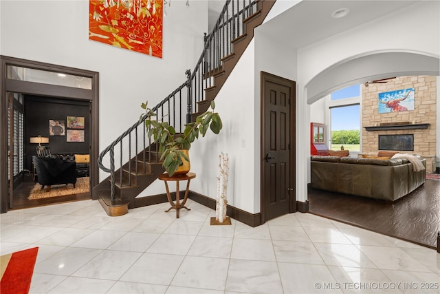 3511 E 181st St S, Bixby, OK 74008 - entrance foyer with stairs, a stone fireplace, arched walkways, a towering ceiling, and baseboards