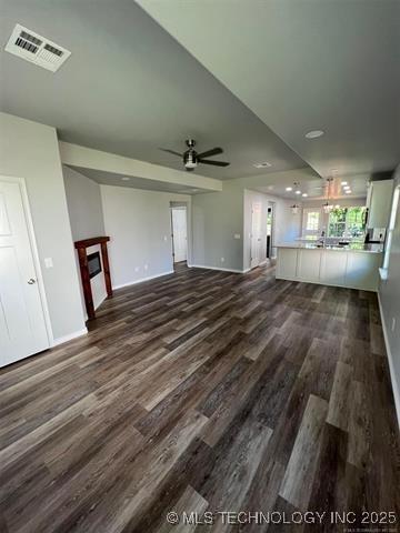 130 W Lincoln Ave, Sapulpa, OK 74066 - unfurnished living room featuring baseboards, dark wood-style flooring, a ceiling fan, and a glass covered fireplace