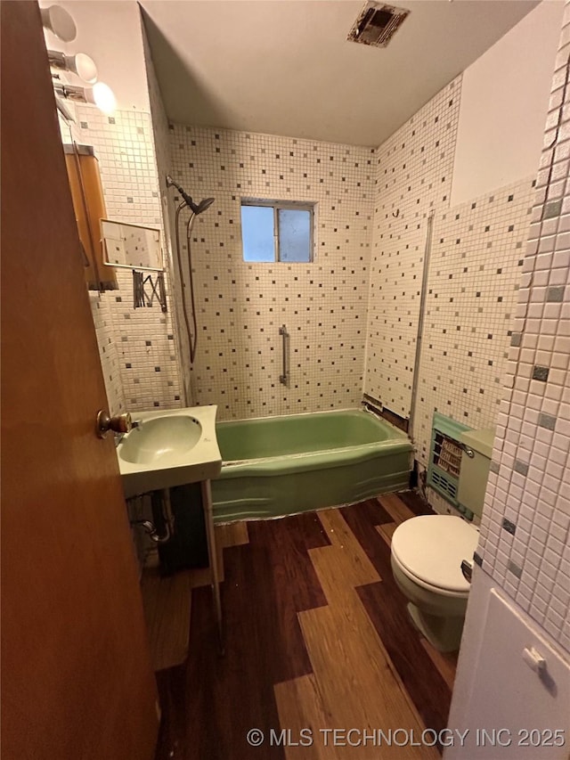 722 S Pine St, Nowata, OK 74048 - full bathroom featuring wood finished floors, tile walls, toilet, a shower, and a tub