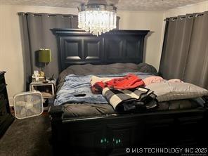 596 Forest Ln, Durant, OK 74701 - bedroom featuring a textured ceiling and a chandelier