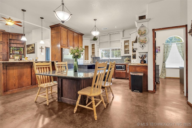 26115 US Highway 70, Bokchito, OK 74726 - kitchen with finished concrete flooring, a ceiling fan, a breakfast bar area, and stainless steel appliances
