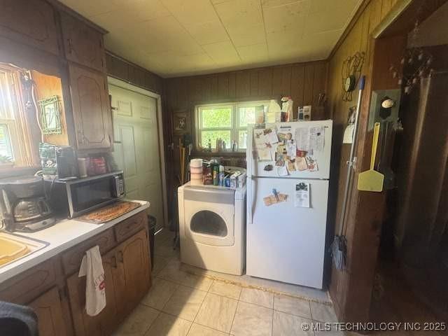 223 W Delaware St, Jay, OK 74346 - kitchen with freestanding refrigerator, washer / dryer, stainless steel microwave, light tile patterned floors, and light countertops