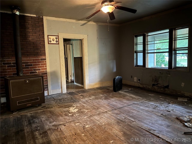 900 S Mabel Ave, Wagoner, OK 74467 - unfurnished living room with ceiling fan, a wood stove, and wood-type flooring