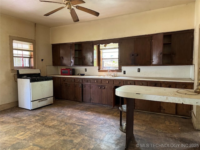 900 S Mabel Ave, Wagoner, OK 74467 - kitchen featuring open shelves, range with gas stovetop, dark brown cabinetry, and a sink
