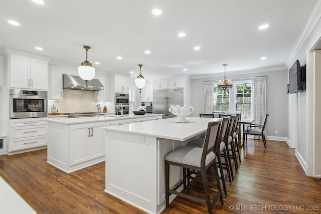 201 E 24th Pl, Tulsa, OK 74114 - kitchen featuring a center island, appliances with stainless steel finishes, wall chimney exhaust hood, ornamental molding, and white cabinets