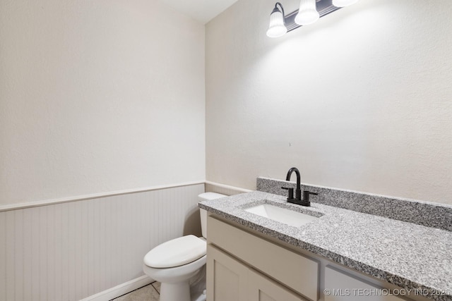 83 Oak St, Durant, OK 74701 - half bathroom featuring toilet, vanity, and wainscoting