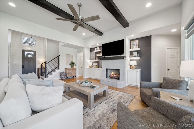 1205 W 88th St S, Tulsa, OK 74132 - living room featuring beam ceiling, a brick fireplace, recessed lighting, light wood-style flooring, and stairs