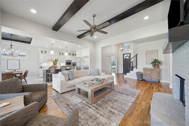 1205 W 88th St S, Tulsa, OK 74132 - living room featuring beam ceiling, a chandelier, stairway, a brick fireplace, and light wood finished floors