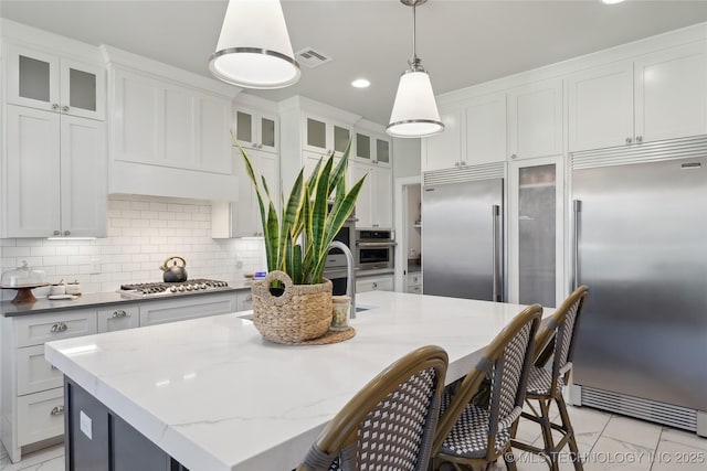 1205 W 88th St S, Tulsa, OK 74132 - kitchen with appliances with stainless steel finishes, a breakfast bar, decorative backsplash, hanging light fixtures, and a kitchen island with sink
