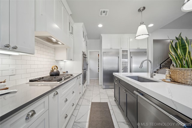 1205 W 88th St S, Tulsa, OK 74132 - kitchen featuring a sink, appliances with stainless steel finishes, white cabinets, light marble finish flooring, and pendant lighting