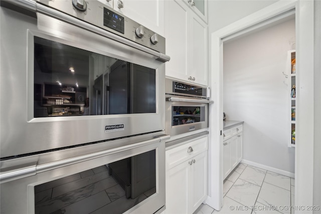 1205 W 88th St S, Tulsa, OK 74132 - kitchen featuring stainless steel double oven, light marble finish flooring, white cabinets, baseboards, and light countertops