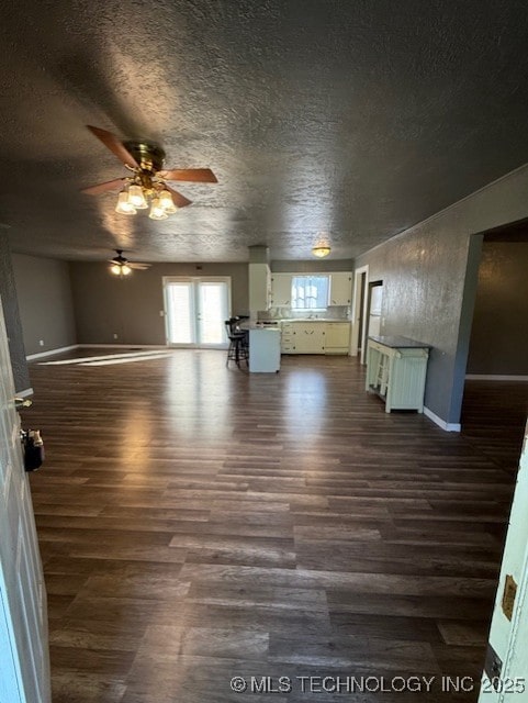 3229 E Cherokee Ave, Sallisaw, OK 74955 - unfurnished living room featuring dark wood-style flooring, a ceiling fan, baseboards, and a textured ceiling