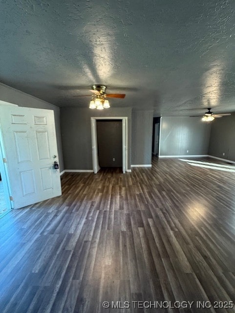 3229 E Cherokee Ave, Sallisaw, OK 74955 - unfurnished living room featuring ceiling fan, baseboards, dark wood-type flooring, and a textured ceiling