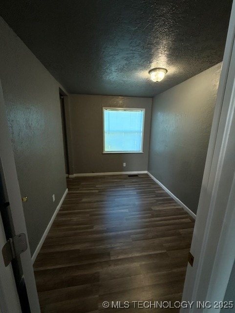 3229 E Cherokee Ave, Sallisaw, OK 74955 - empty room with dark wood-type flooring, a textured ceiling, and baseboards